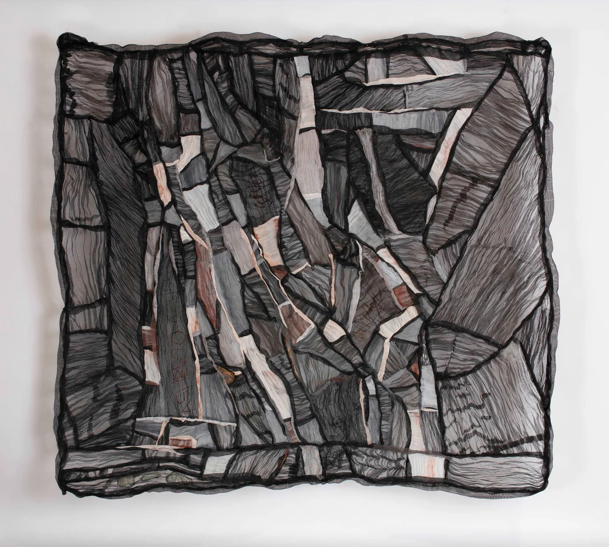 Shadow of a Disappearing Landscape (2024) by J9 Stanton. A black and grey mesh wall work with fractured geometric panels and diagonal folds.